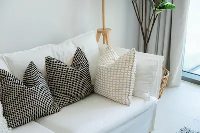 four pillows on a white couch in a living room at Elite Escape Holiday Home - 2 BHK Getaway with Burj Khalifa View and Dubai Mall Access - 1504 in Dubai