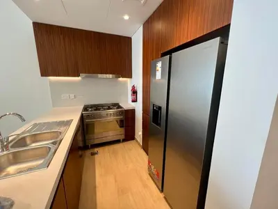 a kitchen with a stainless steel refrigerator and wooden cabinets at Brand New 2BR in La Rive with SeaView, Pool & Gym in Dubai