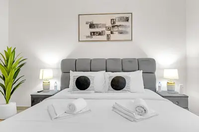 a bedroom with a large white bed with two towels at 2 BR in Forte, Close to Dubai Mall with Pool and Gym in Dubai