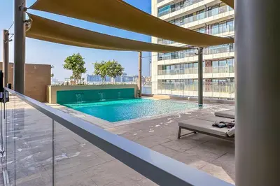 a swimming pool in a building with an umbrella at Luxe Living in Beachfront 2 Bedroom in Dubai Marina in Dubai