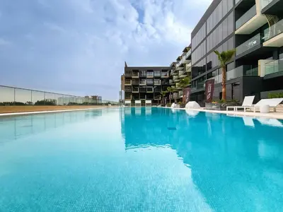 a large swimming pool next to a building at Binghatti Crescent, Jumeirah Village Circle in Dubai