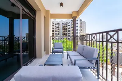 a balcony with a couch and chairs on a balcony at Peaceful 2BR Retreat Near Burj Al Arab in Dubai