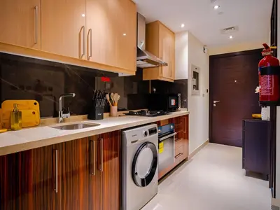 a kitchen with wooden cabinets and a washer and dryer at Cozy Studio with Burj Khalifa Views in Dubai