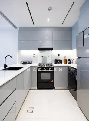a kitchen with white cabinets and a black stove at Stylish 1br Business Bay W Burj Views in Dubai