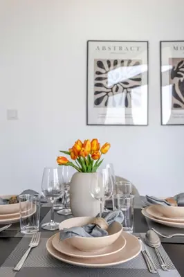 a dining room table with plates and glasses and flowers at Frank Porter - The Lofts West in Dubai