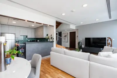 a living room with white furniture and a kitchen at Burj Daman, DIFC Dubai - Mint Stay in Dubai