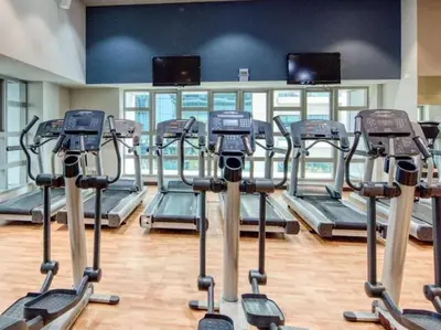 a gym with rows of tread machines in a room at Stunning Marina View! CoLiving Rooms in Princess Tower Marina in Dubai