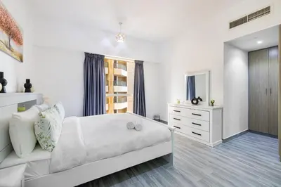 a white bedroom with a white bed and a dresser at Upgraded 3BR Jacuzzi & Comfort at JBR in Dubai