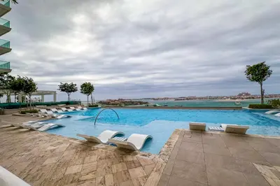 a large swimming pool with white lounge chairs in a building at Privet Beach 2BR in Dubai Marina in Dubai