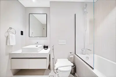 a white bathroom with a sink and a toilet at Silkhaus Sea & Palm View 1BDR at Marina Vista in Dubai