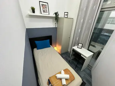 a small bedroom with a bed and a table at Partition Room 5 Mins to Mashreq Metro in Dubai