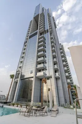 a tall building with chairs and a pool in front of it at GuestReady Holiday Homes - Arabian Elegance in JVC in Dubai