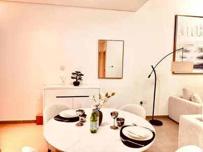 a white living room with a table and chairs at Park Heights Deluxe 1bedroom in Dubai