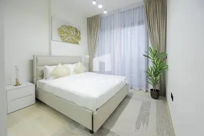 a white bedroom with a large bed and a window at Modern 1br Jvc Balcony & Free Parking Pool in Dubai
