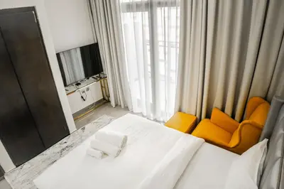 a hotel room with a white bed and an orange chair at Perfect Studio Apartment Near to Metro Station in Dubai