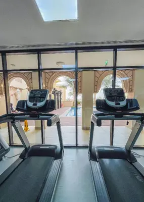 two treadmills in a gym with a view of a pool at Veluxa - Fantastic 1 Bed - in Jumeirah Golf Estate! in Dubai