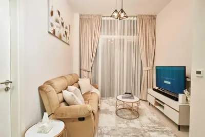 a living room with a couch and a television at Cosy 1 Bedroom in Damac Hills | OFEX in Dubai