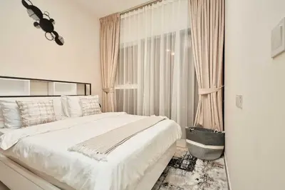 a white bedroom with a bed and a window at Cosy 1 Bedroom in Damac Hills | OFEX in Dubai
