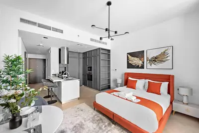 a bedroom with a bed and a desk and a kitchen at StoneTree - Brand new Studio in Mohammed Bin Rashid City in Dubai