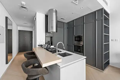 a kitchen with black cabinets and a kitchen island with stools at StoneTree - Brand new Studio in Mohammed Bin Rashid City in Dubai