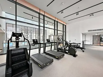a gym with treadmills and ellipticals in a room with windows at StoneTree - Brand new Studio in Mohammed Bin Rashid City in Dubai