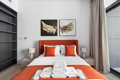 a bedroom with a large bed with orange pillows at StoneTree - Brand new Studio in Mohammed Bin Rashid City in Dubai