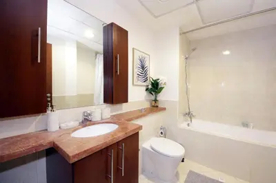 a bathroom with a sink and a toilet and a tub at New Arabian The Links Canal 1 BR The Greens in Dubai