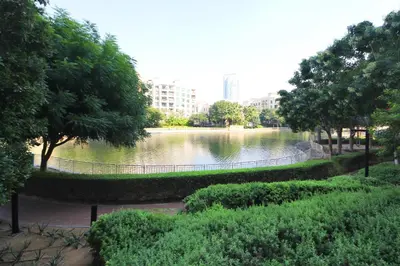 a park with a lake with trees and buildings at New Arabian The Links Canal 1 BR The Greens in Dubai