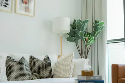 a living room with a couch with pillows and a lamp at Elite Escape Holiday Home - 2 BHK Getaway with Burj Khalifa View and Dubai Mall Access - 1507 in Dubai