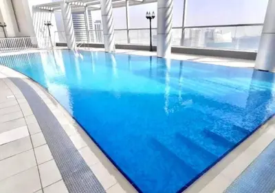 a large swimming pool with blue water in a building at RH- High-Floor Splendor, 2-Bedroom Gem in Downtown in Dubai