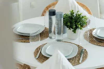 a white table with plates and napkins and a plant at Elite Escape Holiday Home - 2 BHK Getaway with Dubai Mall Access - 1508 in Dubai
