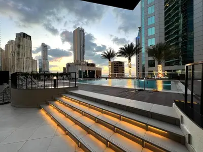 a building with a swimming pool and a city skyline at 1 BR Flat, Luxury amenities, Near JBR Beach & Club with FREE Parking in JBR in Dubai