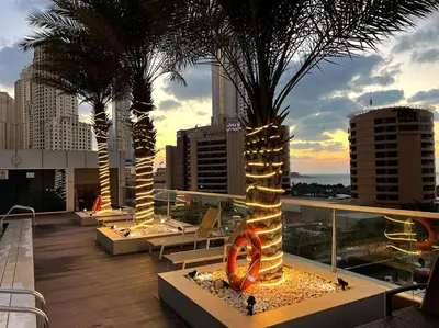 a balcony with palm trees and lights on a building at 1 BR Flat, Luxury amenities, Near JBR Beach & Club with FREE Parking in JBR in Dubai