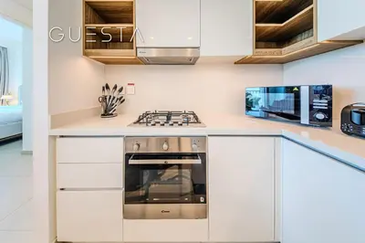 a kitchen with white cabinets and a stove at Downtown Views II by Emaar, Downtown Dubai in Dubai