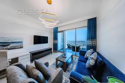 a living room with a blue couch and a tv at Downtown Views II by Emaar, Downtown Dubai in Dubai