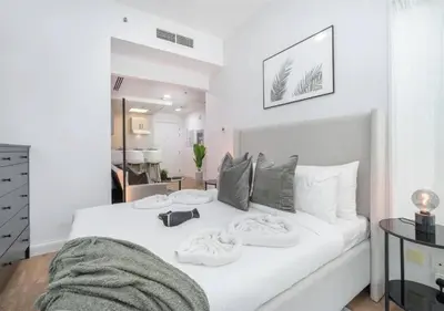 a bedroom with a white bed with towels on it at HAVN - Studio Apartment in JLT, with Lake Views in Dubai