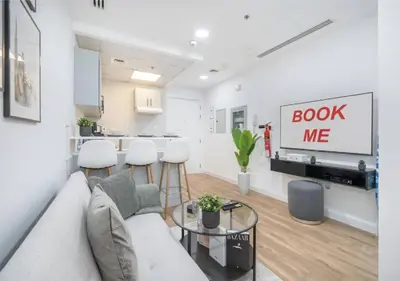 a living room with a couch and a book me sign at HAVN - Studio Apartment in JLT, with Lake Views in Dubai