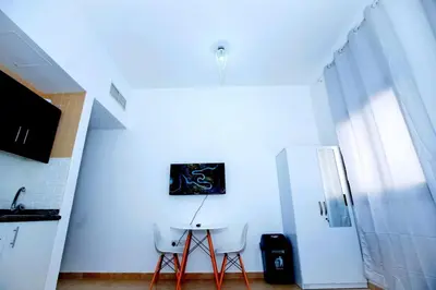 a white kitchen with two chairs and a refrigerator at Your Silicon Oasis Comfort Haven in Dubai