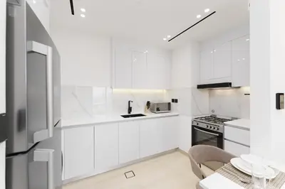 a white kitchen with white cabinets and a table at Luxury Living in 1 bedroom apartment in JVC in Dubai