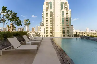 a hotel swimming pool with lounge chairs and buildings at Luxury Living in 1 bedroom apartment in JVC in Dubai