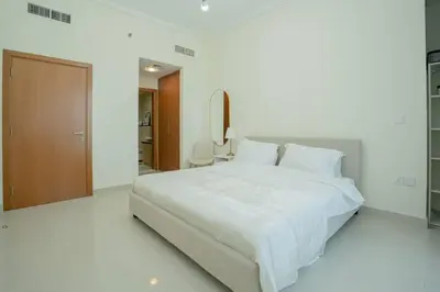 a white bedroom with a large bed with white sheets at Cozy Spacious Apartment 1BR in Dubai