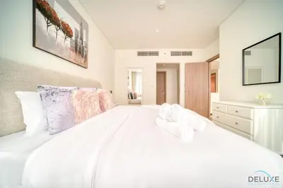 a bedroom with a white bed with towels on it at Special Offer Stylish 1BR with Scenic Views & Pool by Deluxe Holiday Homes in Dubai