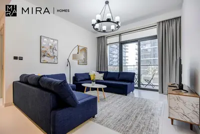 a living room with two blue couches and a tv at Mira Holiday Homes-Marina Vista Emaar Beachfront in Dubai