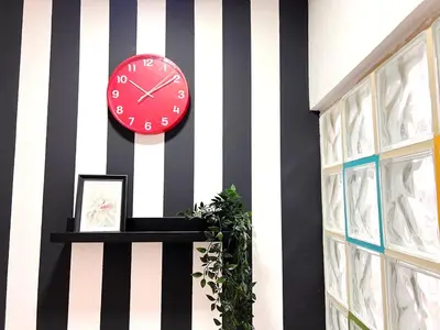 a red clock on a black and white striped wall at Relaxing Closed Partition Room in Tecom Near Metro in Dubai
