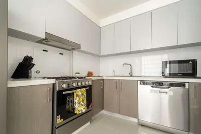 a white kitchen with a stove and a dishwasher at Frank Porter - Forte Tower 1 in Dubai