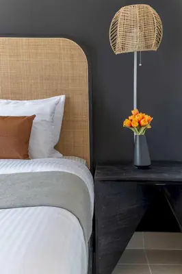 a bed with a vase of flowers on a table with a lamp at Frank Porter - Forte Tower 1 in Dubai