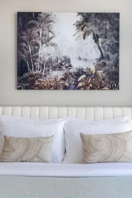 a painting above a bed with white pillows at Frank Porter - Forte Tower 1 in Dubai