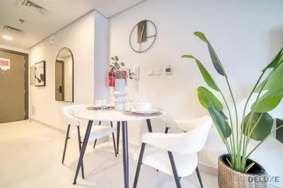 a dining room with a table and chairs and a plant at Stylish Studio Apartment at Casa Grande, JVC by Deluxe Holiday Homes in Dubai