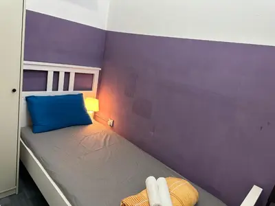 a small bedroom with a bed with a blue pillow at Calm Partition Room Near Mashreq Metro in Dubai