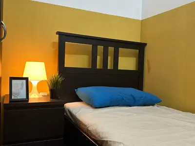 a bedroom with a bed with a blue pillow and a lamp at Prime Partition Room in Al Barsha 1 Near Metro in Dubai